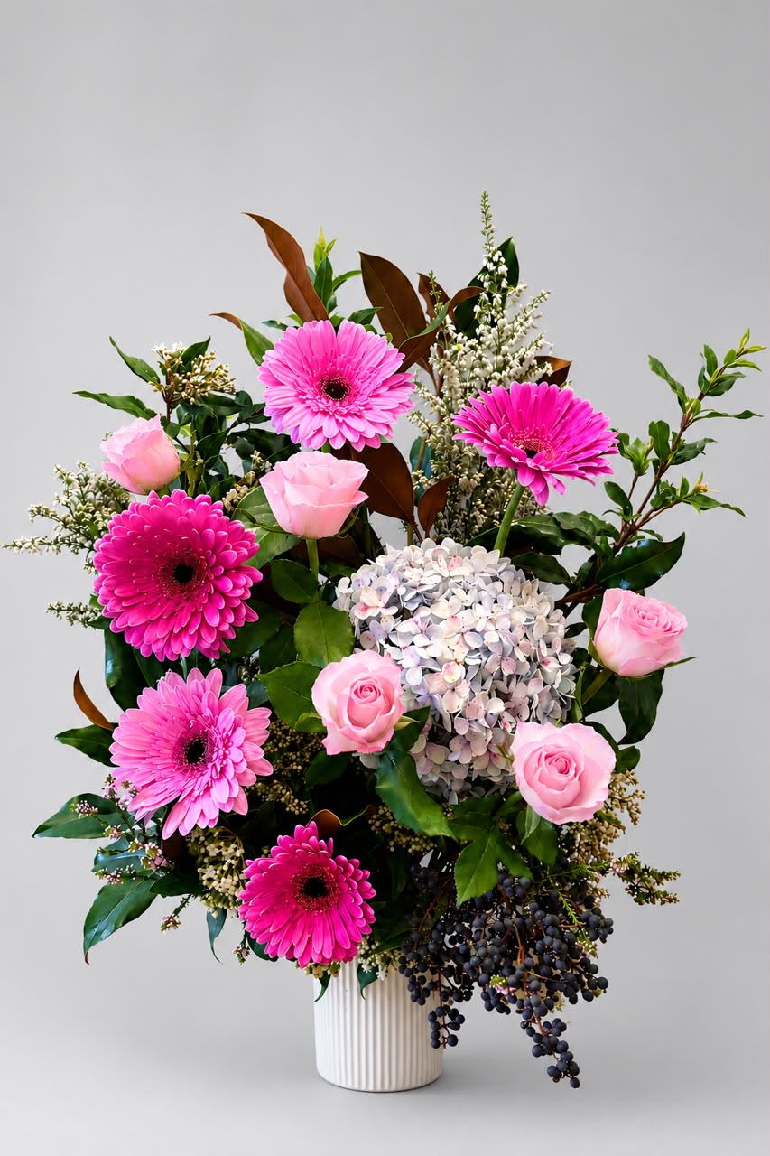 A beautiful mixed arrangement of seasonal roses, gerberas, hydrangea, and premium foliage, elegantly presented in a ceramic vase A beautiful mixed arrangement of seasonal roses, gerberas, hydrangea, and premium foliage, elegantly presented in a ceramic vase